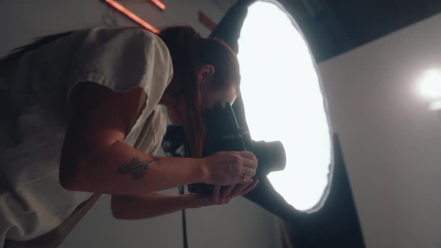 Female photographer taking pictures of a model in a studio