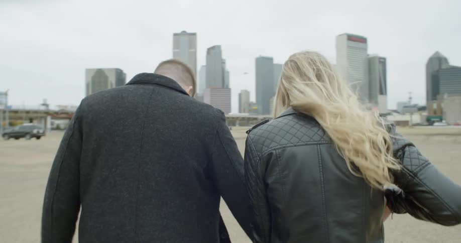 A couple walks on the beach near a city