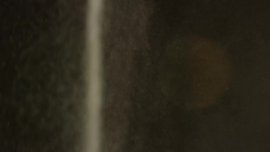 Closeup of white sand or dust cascading against a dark backdrop