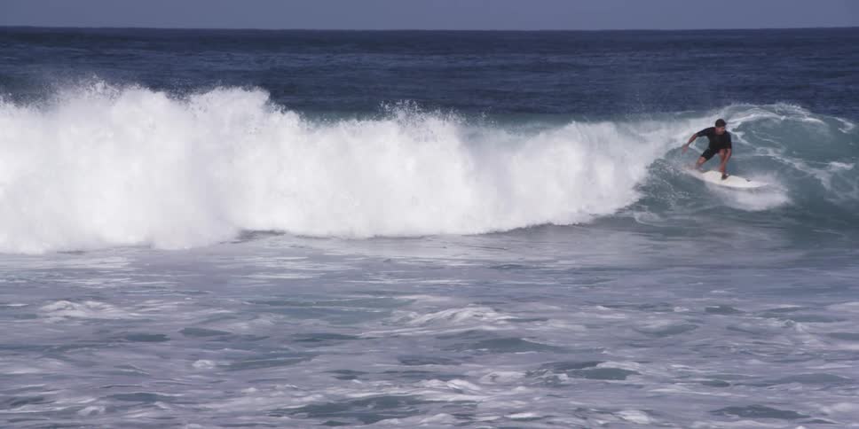 A surfer is riding a wave on a sunny day