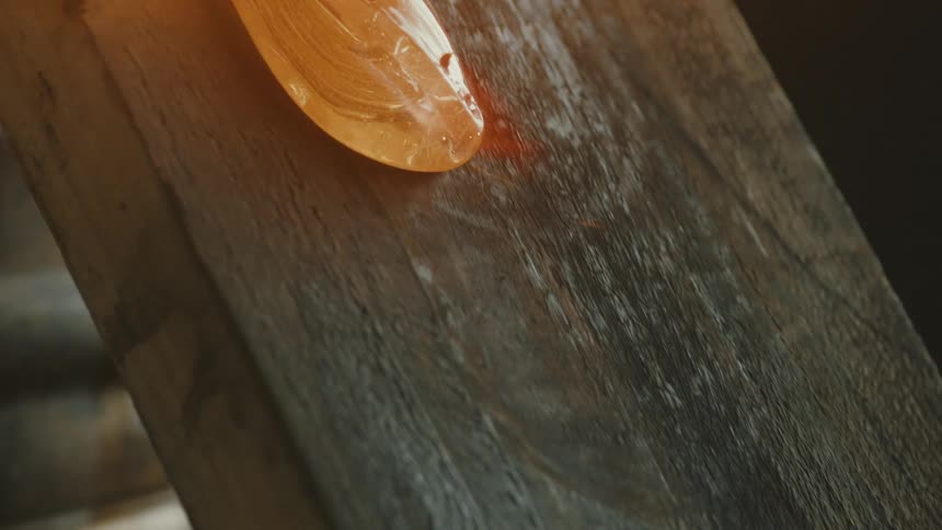 Molten glass over a piece of wood burning from the intense heat with flames and smoke rising