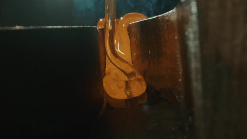 Closeup of molten glass flowing into a mold
