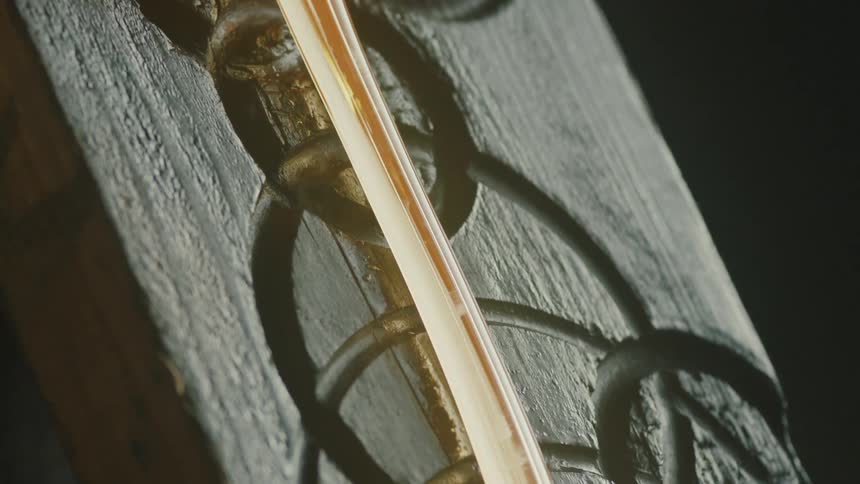 Molten glass over a carved piece of wood burning from the intense heat with flames and smoke rising