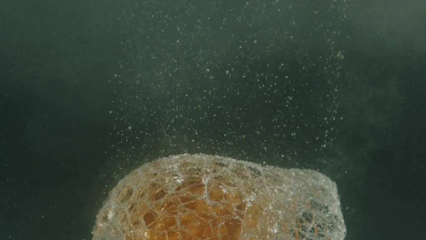 Abstract forged glass cooling inside water with air droplets rising