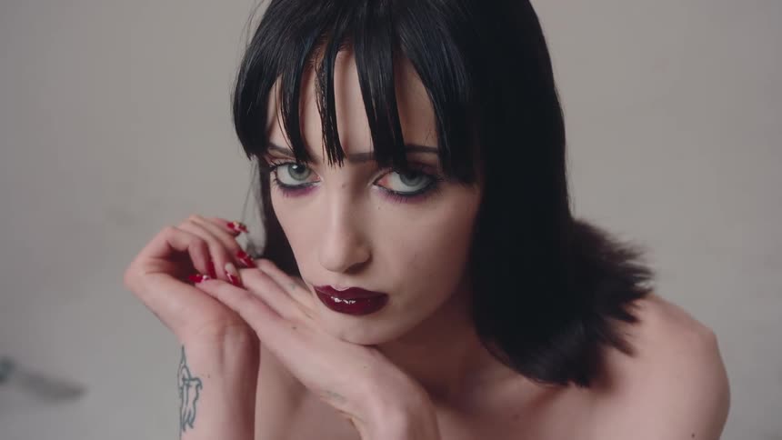 Closeup of a model with bright red lipstick big eyes and long black hair posing for the camera in a studio