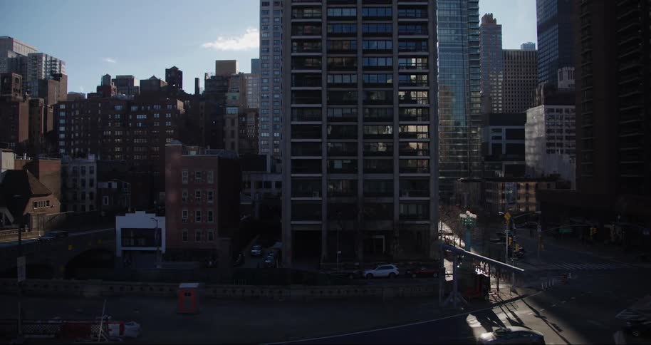 The camera pans down from the horizon over an empty city street toward a brightly lit intersection with cars and skyscrapers