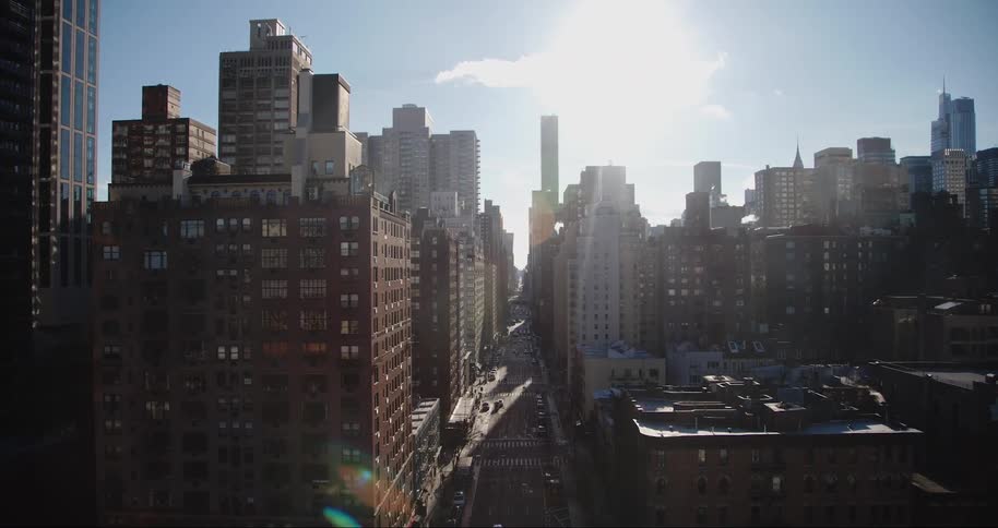 Sun glares down onto downtown city buildings on a cloudy day