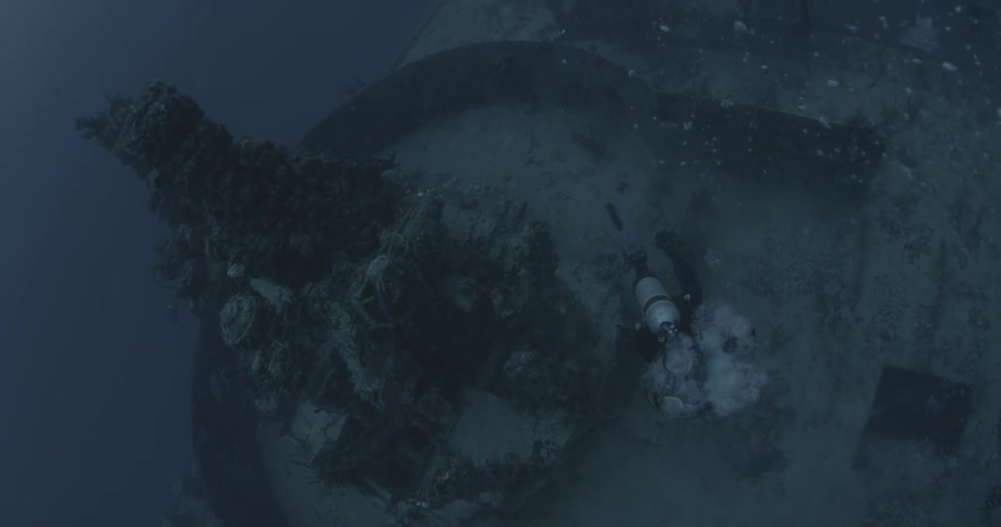 A diver swims near ship wreckage in the ocean