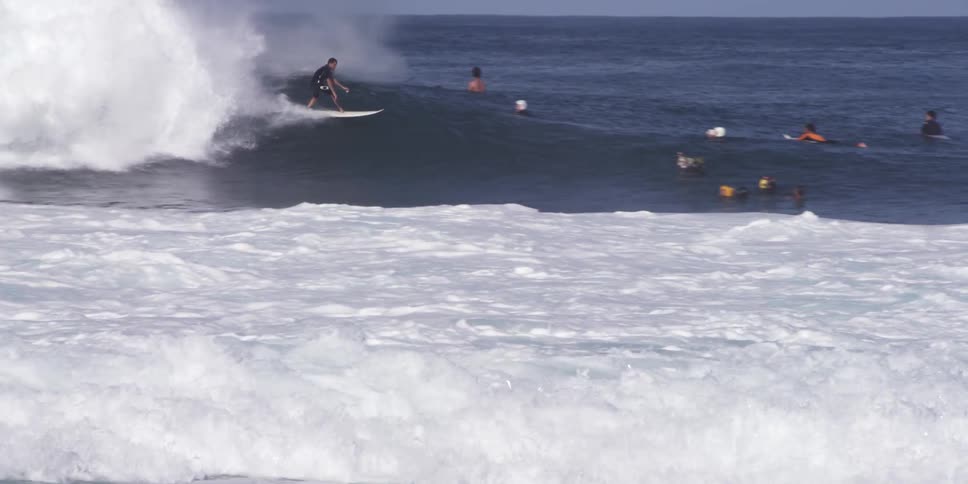 A beach full of people and a surfer