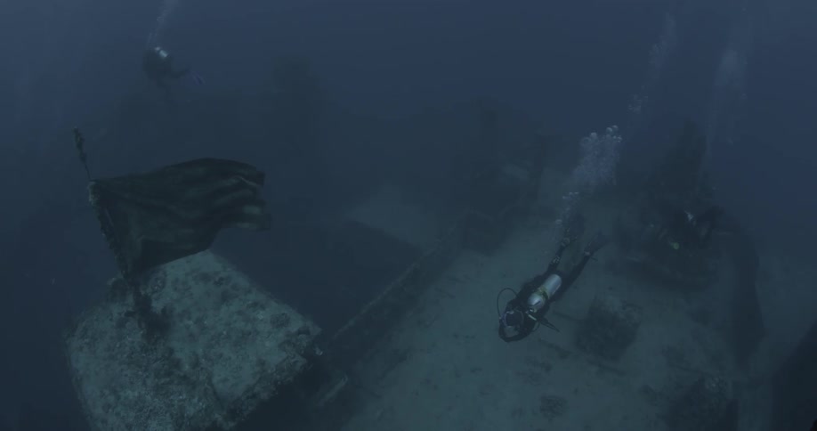 Scuba divers swim around a sunken ship