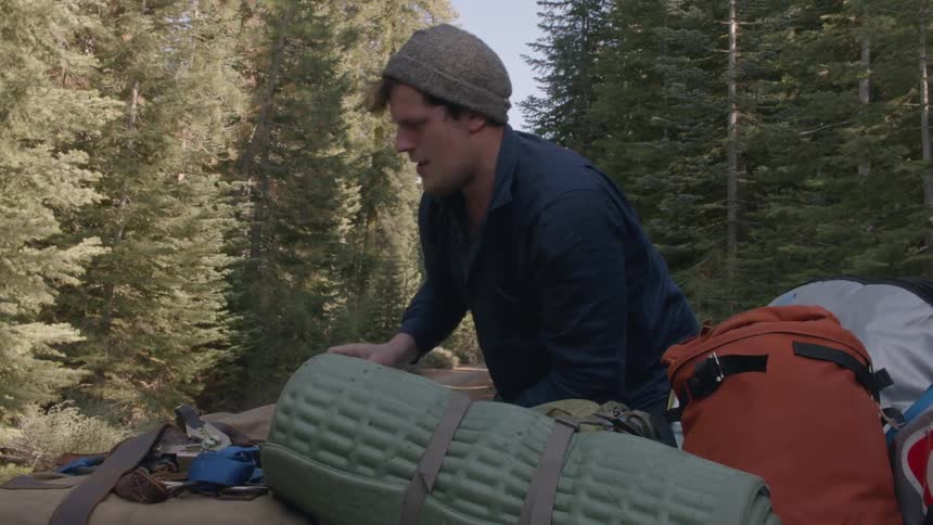 Person grabbing bag from camping gear on a sunny day