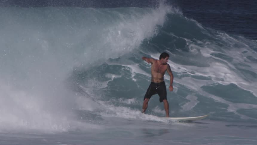 Shirtless man surfs on a clear day