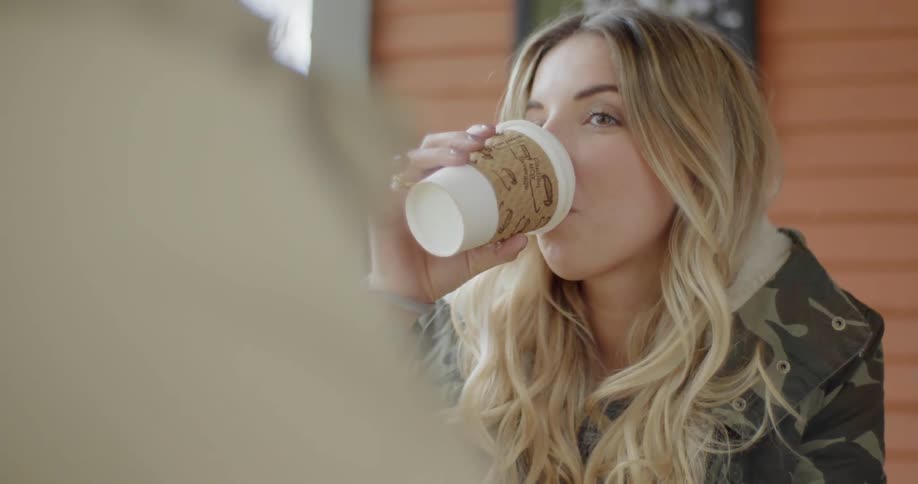 A woman takes a drink from a cup outside