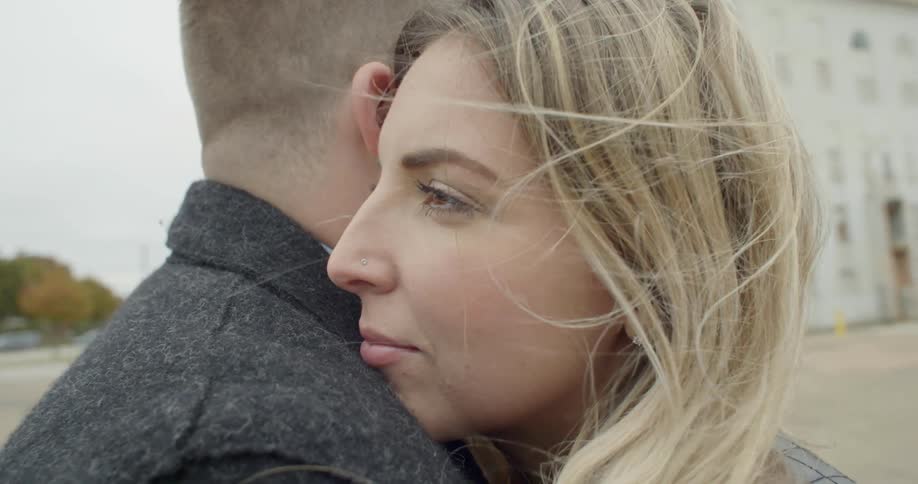 A man and woman hug on a windy day