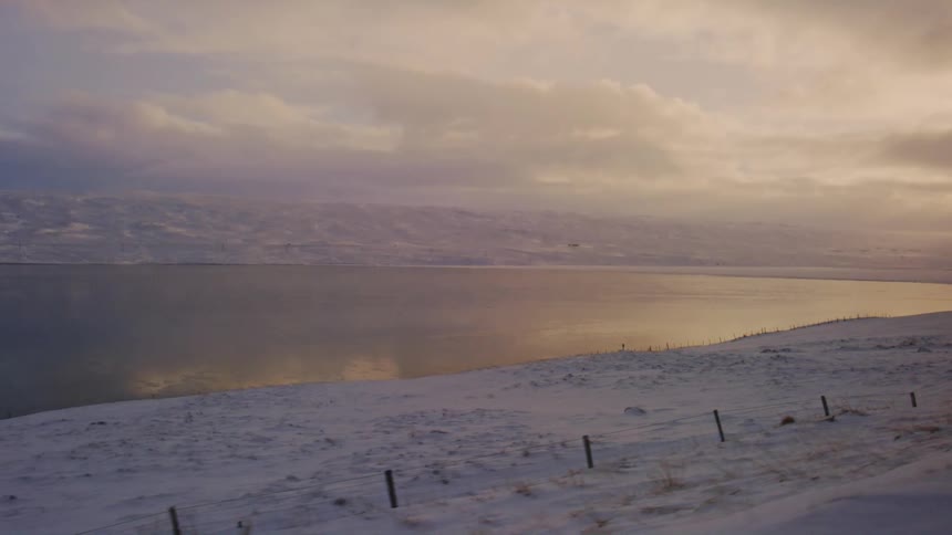Landscape of a lake reflecting the sky surrounded by snowy mountains