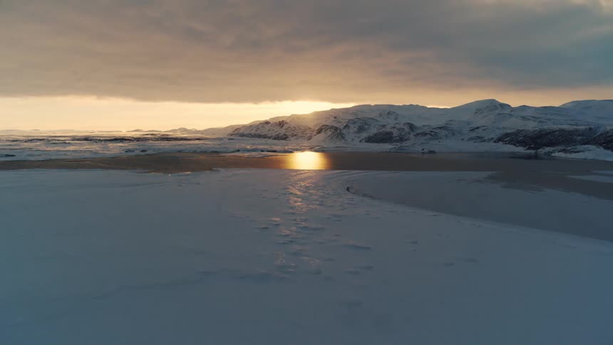 Aerial shot of a lake surrounded by snowy mountains