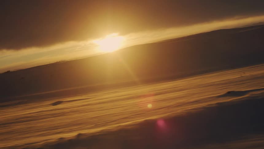 The landscape is covered in heavy snow at sunrise