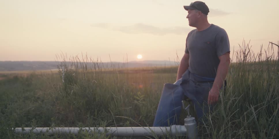 Man in a field looking at a lever of an irrigation system