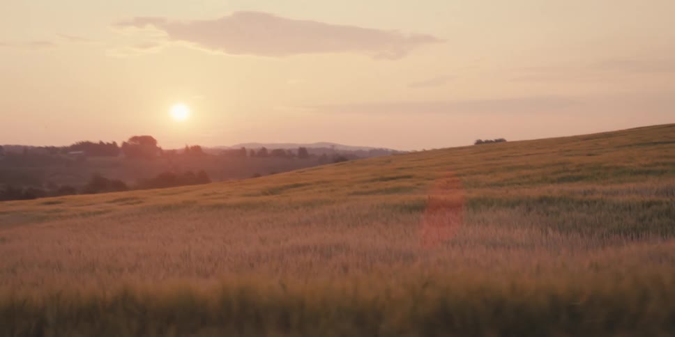 Landscape of hills and lawns with dust on the horizon
