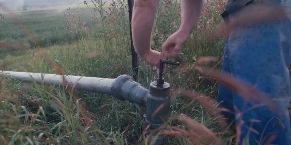 Hands turning the valve of an irrigation system