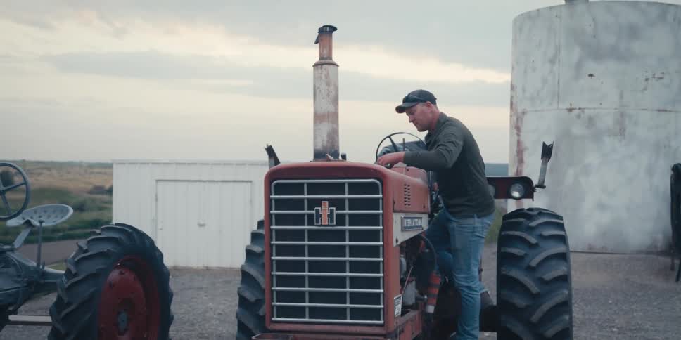 A man is repairing his tractor on the farm