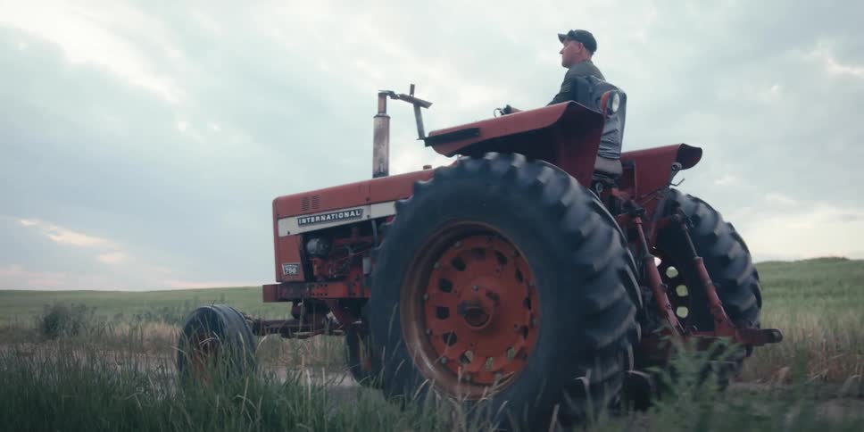 Man driving a red tractor in an agricultural area