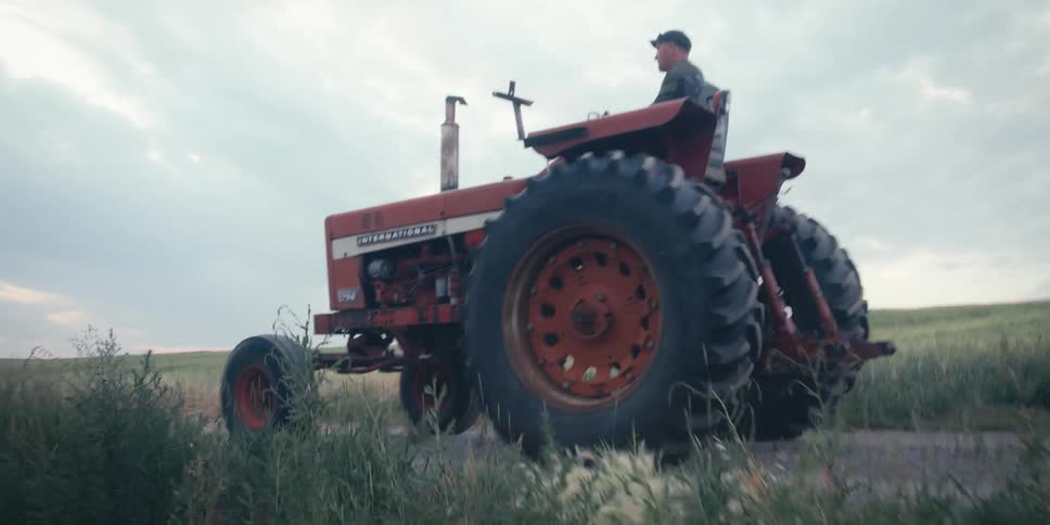 Man driving a red tractor in a rural area