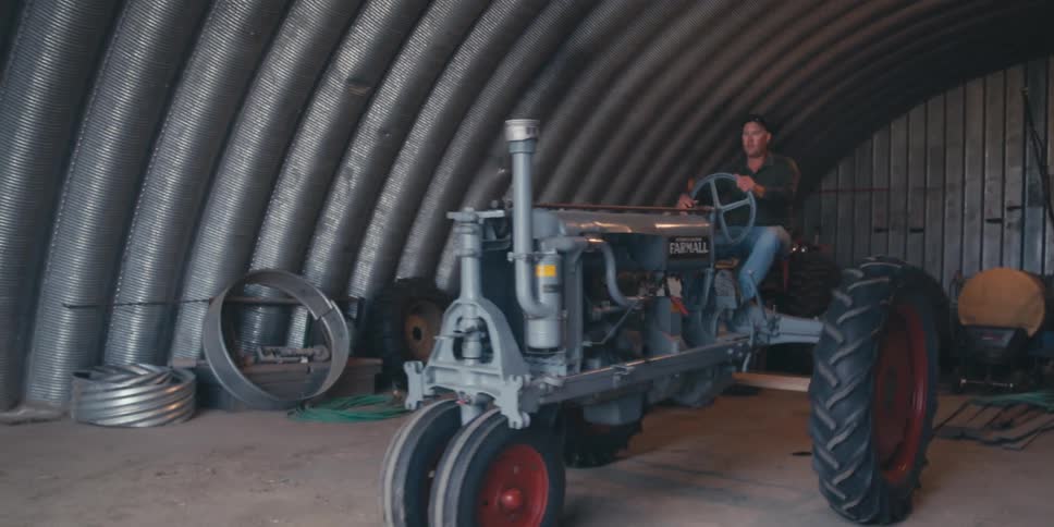 Man leaving a shed with a farm tractor