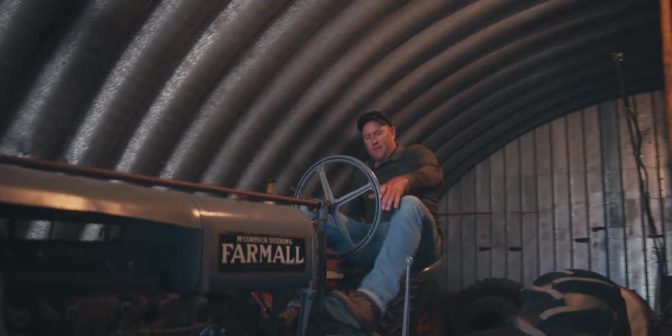 A man jumps onto a tractor
