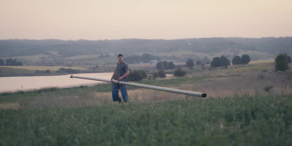 A man carries a long irrigation pipe on the farm