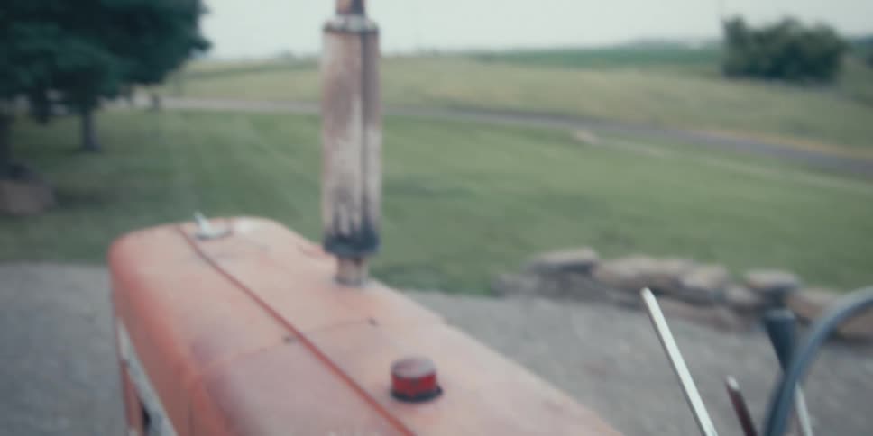 Pair of hands of a man steering the steering wheel of a tractor in a rural area