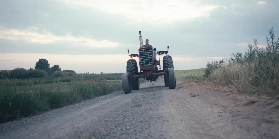 A man drives a tractor on a dirt road