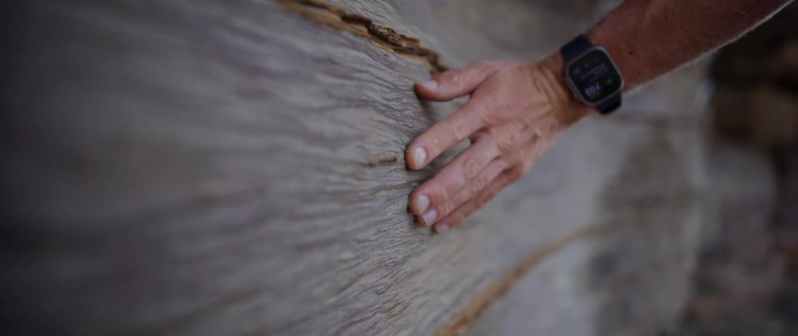 Close up of a hand with a clock ticking on a wooden surface