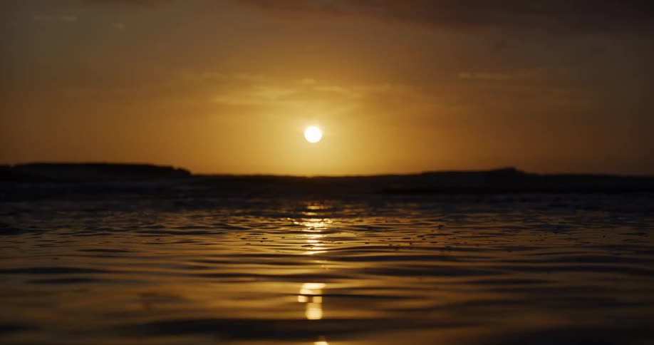 Landscape of calm ocean and golden sun on the horizon