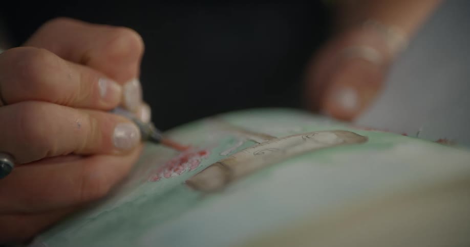 Close up of a womans hand holding a paintbrush and painting