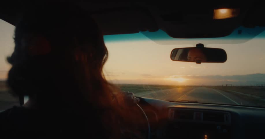 The wind blows a womans hair as she is driving
