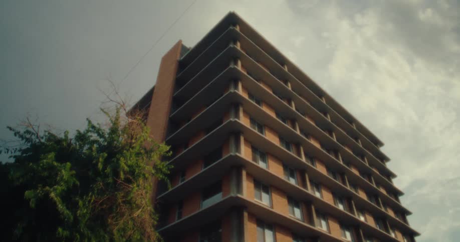 Upward view of a standardized urban building against a cloudy sky