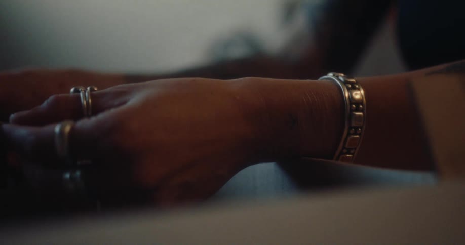Close up of a pair of womans hands wearing jewelry and holding an object