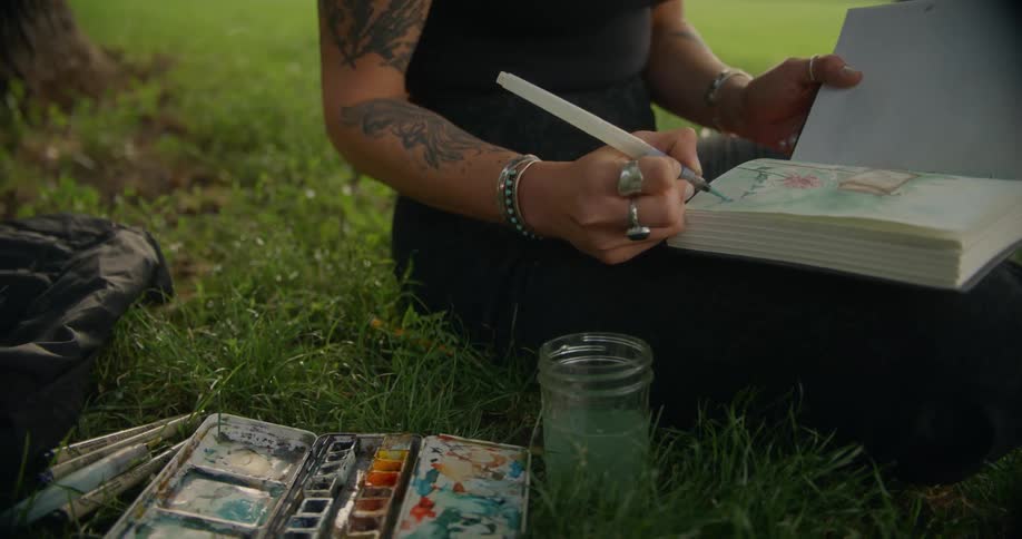Woman sitting on the grass and drawing in a book