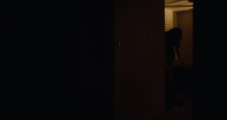 A woman walks through the dark hallway