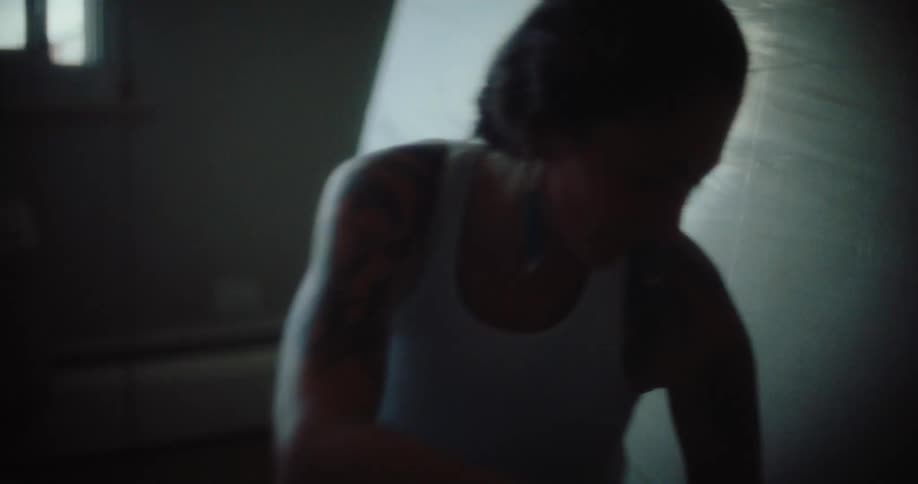 A woman sits on the floor in a dimly lit room preparing to rearrange furniture