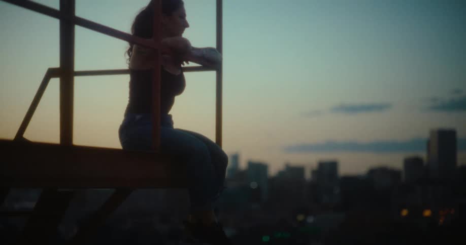 A womans feet dangle from the roof she is sitting on