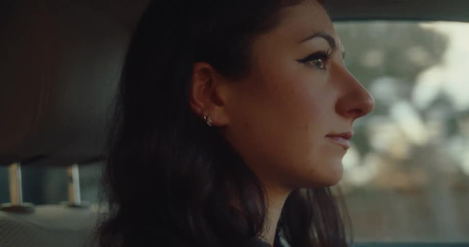 A woman driving a car through the city on a sunny morning