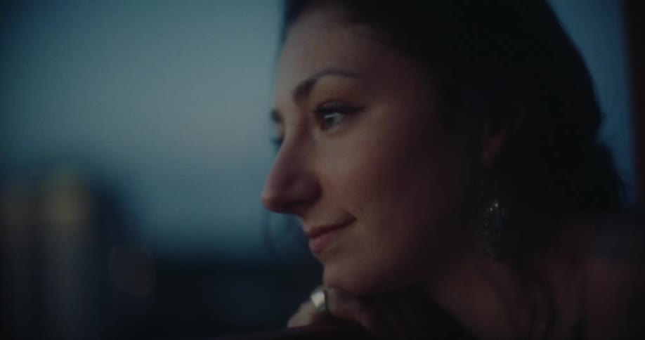 Close up of a woman face with hair flowing in the wind gazing through a window in the evening