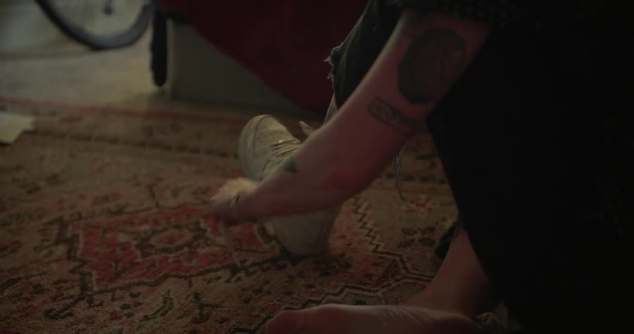 Woman sitting on carpet tying her sneakers
