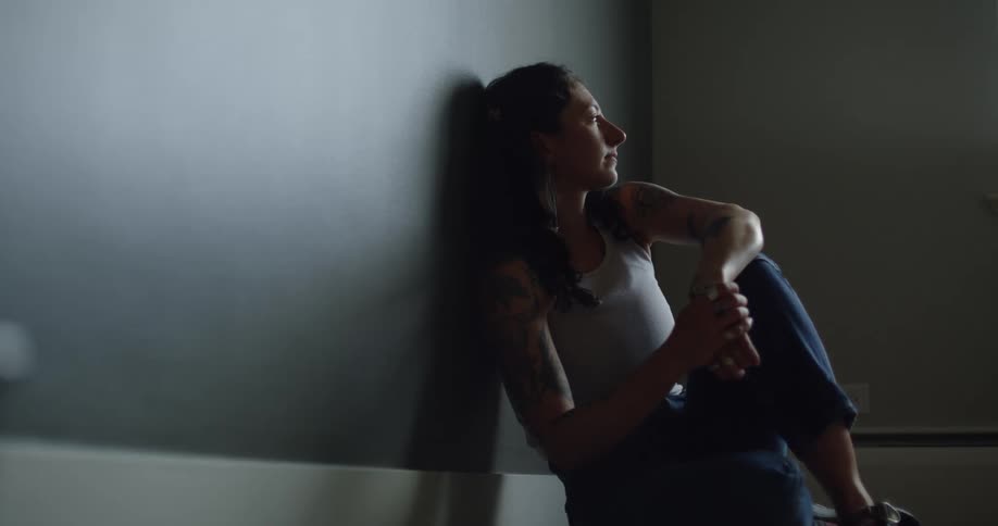 Woman sitting on the floor with thoughtful facial expression