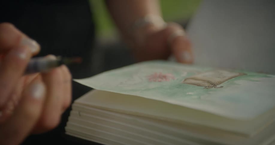 Womans hand with a brush painting on a book