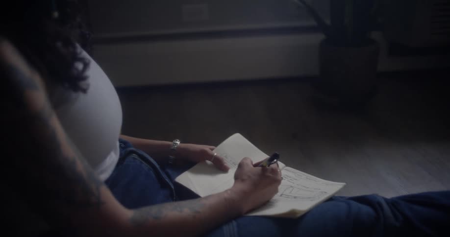 Woman sitting in living room and writing on a paper