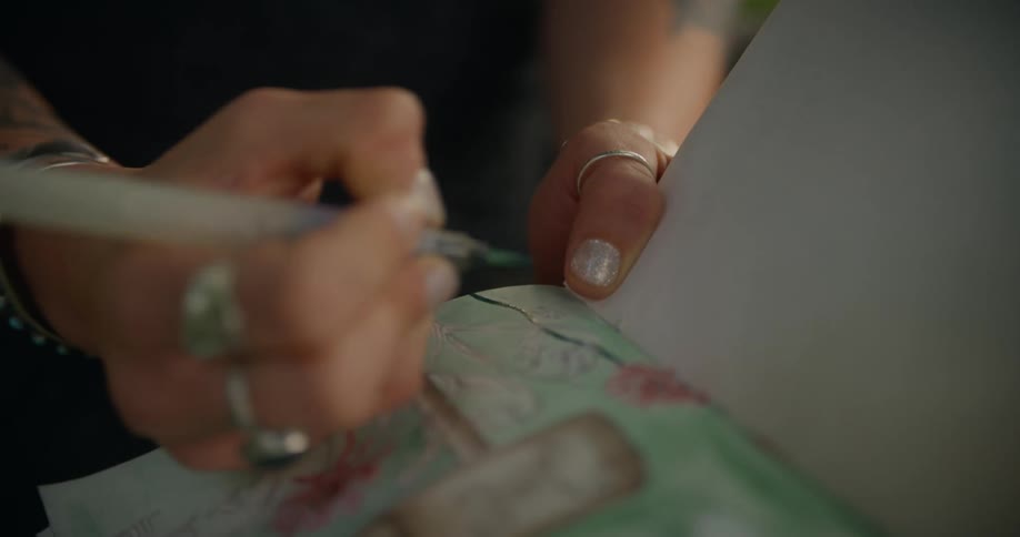 Close up of a womans hand with a paintbrush painting a design