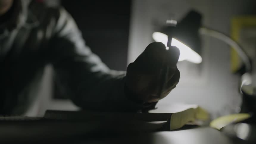 A person twirls a pen over a book